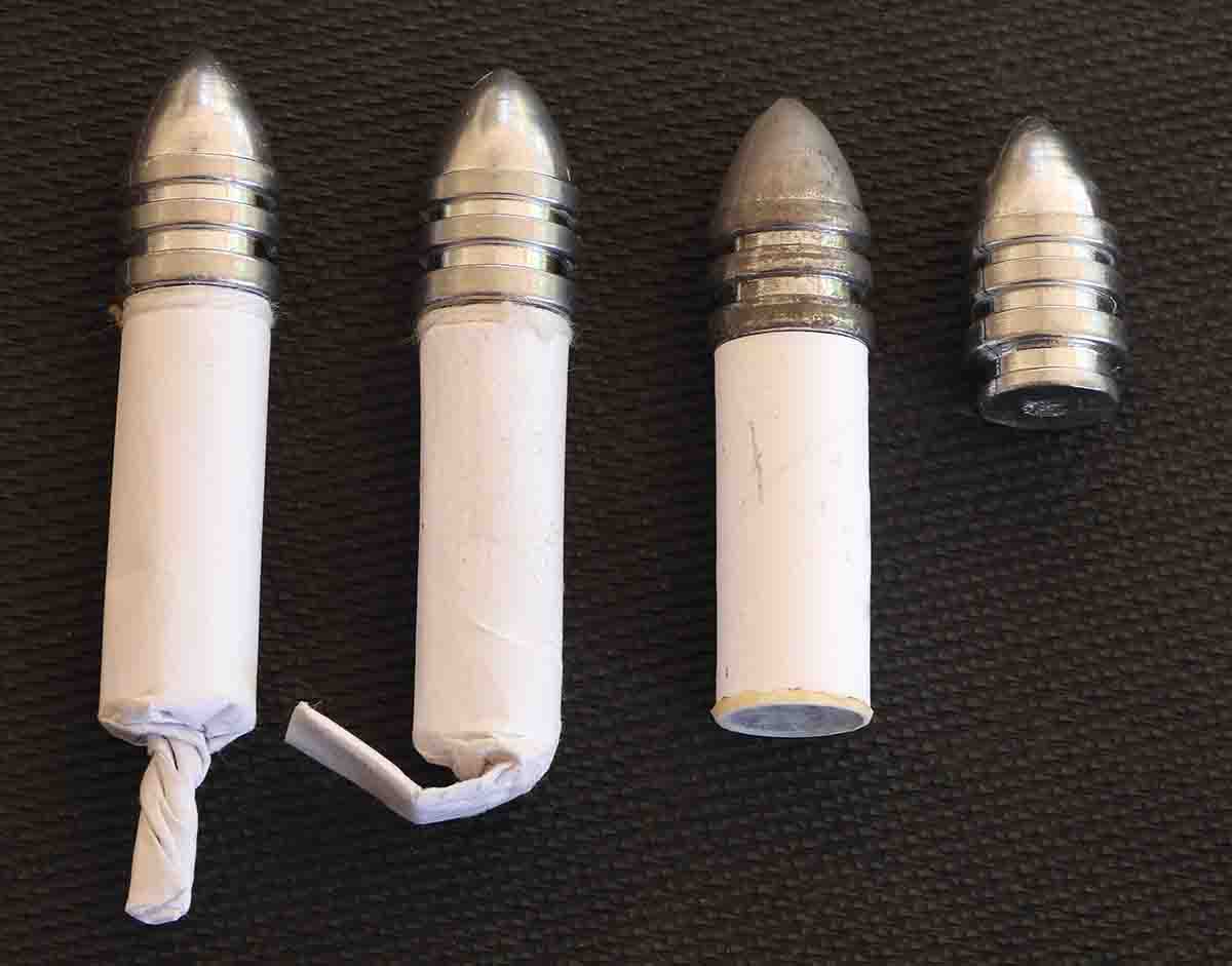 Three types of paper cartridges used for the test, the first with a twisted tail, the second with a folded tail, and the third with a flat base that equals the length of the chamber. The naked bullet shows the full bullet length with “ringtail.”